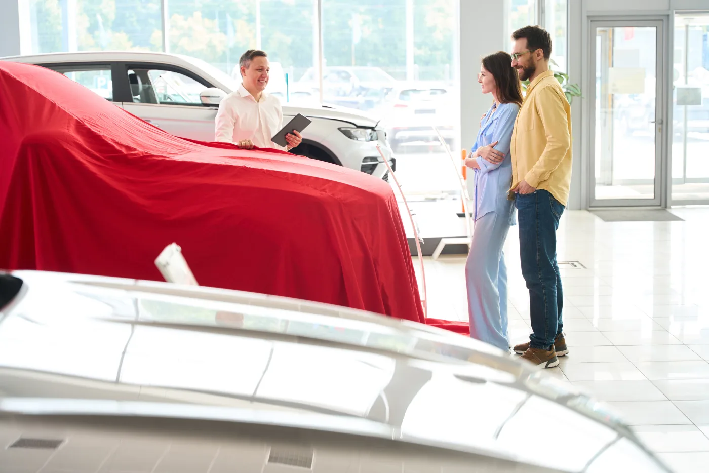 Dealership consultant revealing a new car to a couple